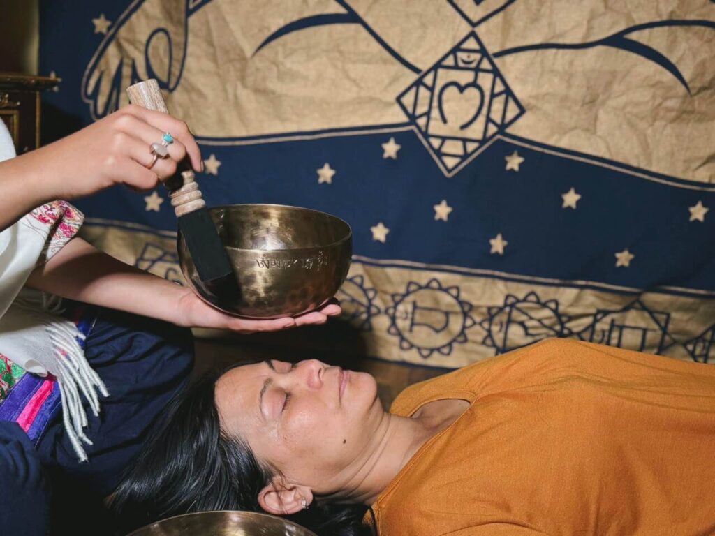 a woman attending a singing bowl sound healing session using a singing bowl